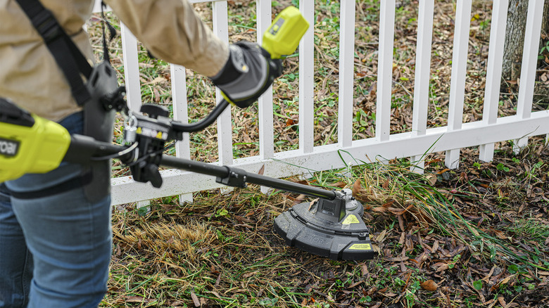 trimmer cutting near fence