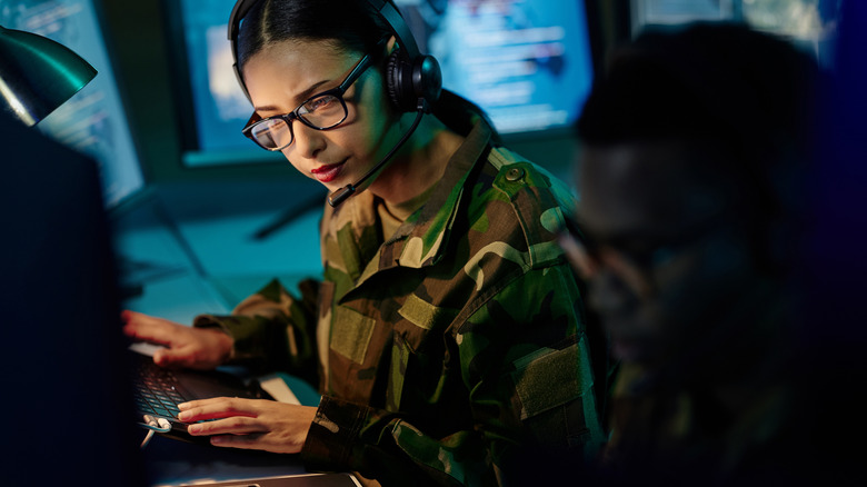 A female Soldier working on a computer system with headphones