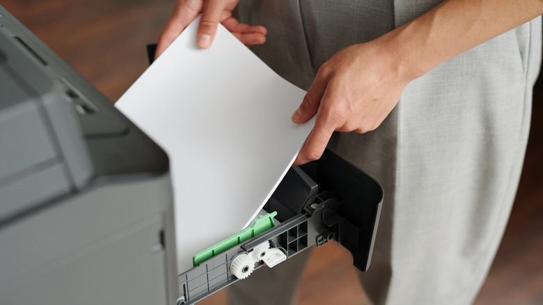 person loading paper into printer