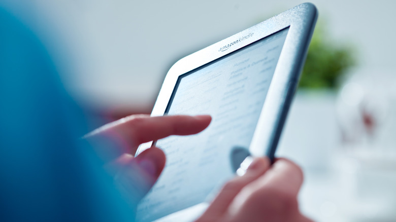 Person scrolling Kindle with finger 