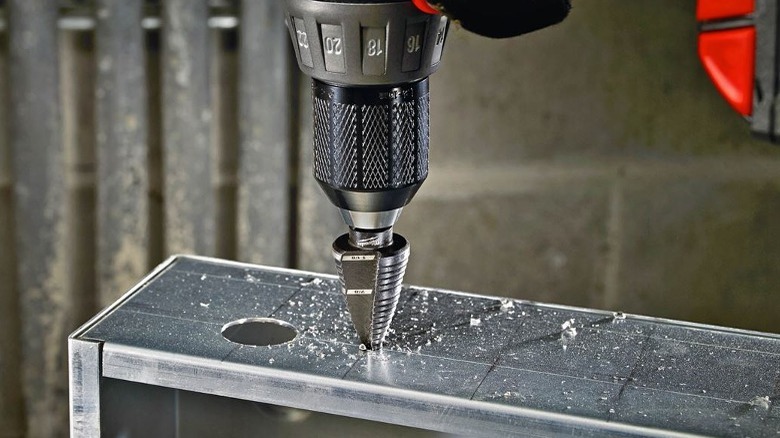 Person drilling metal with step bit