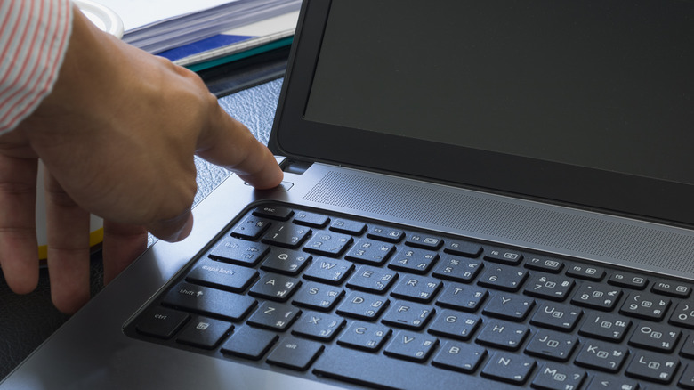 Man's hand turning off laptop