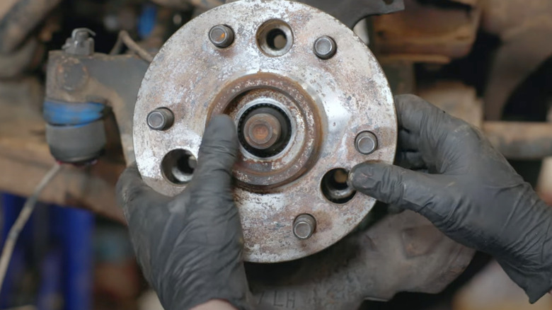 mechanic with black gloves removing wheel hub and bearing assembly