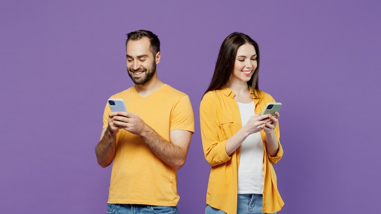 smiling people with smartphones on purple background