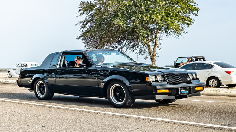 Black 1987 Buick GNX car on road with passengers inside