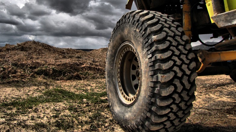 Close-up of vehicle driving off-road with storm clouds in the distance