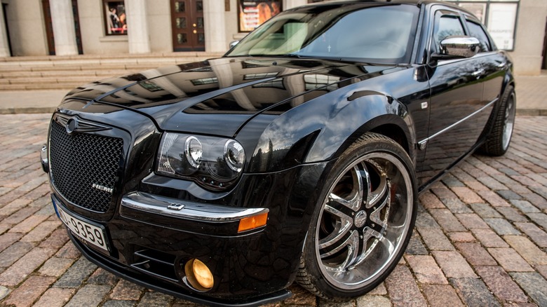 Black Chrysler 300C HEMI parked on a brick street in the city