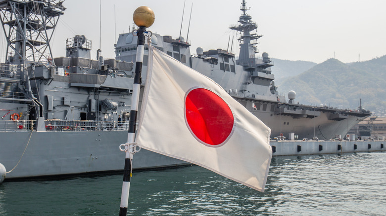 Japanese flag flies in front of warship in Kure