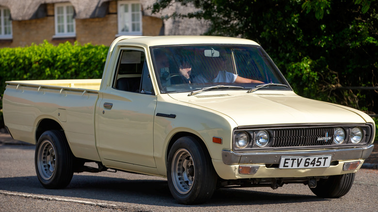 yellow Datsun truck parked on street