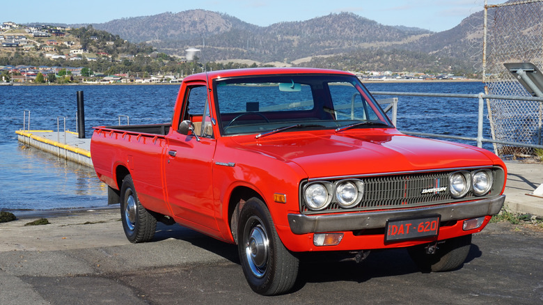 red Datsun truck parked at boat ramp