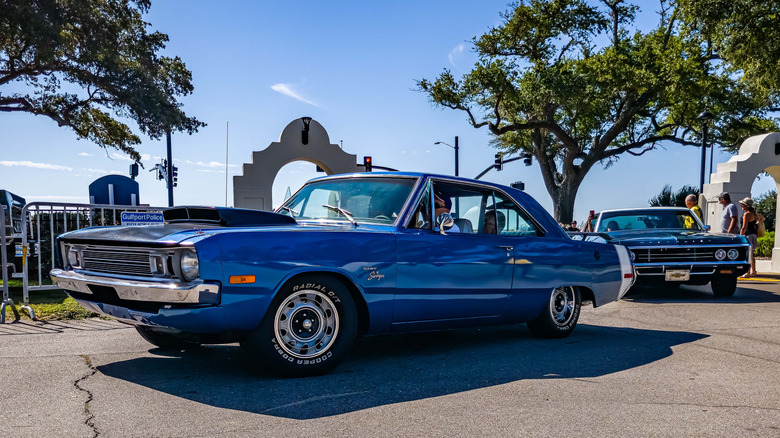 Blue colored Dodge Dart Swinger parked near gated entrance