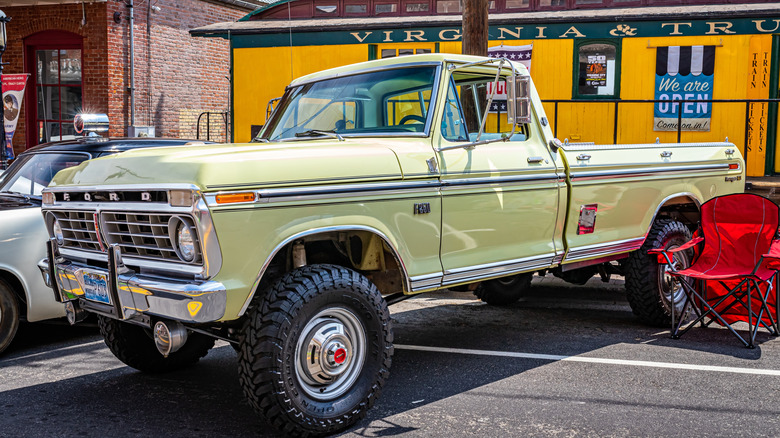 a yellow 1975 Ford F-250 pickup truck parked at an outdoor auto show