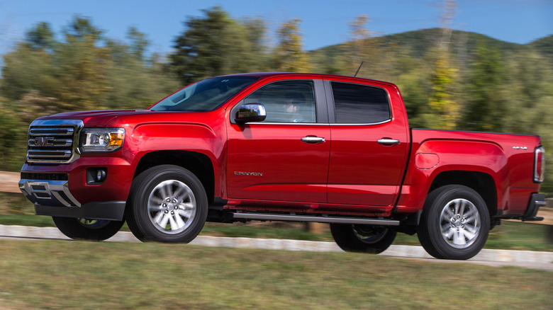 Sideview of red GMC Canyon truck driving on a road.