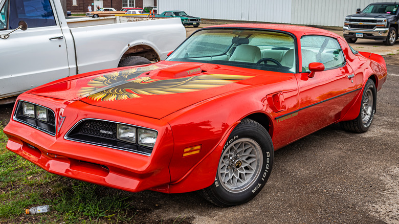 A 1978 Pontiac Firebird Trans Am with snowflake wheels parked.