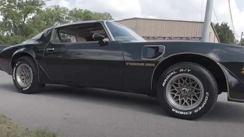 A black 1979 Pontiac Trans Am with chrome snowflake wheels.