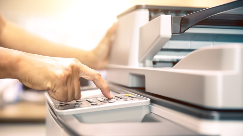 hand pressing fax machine buttons