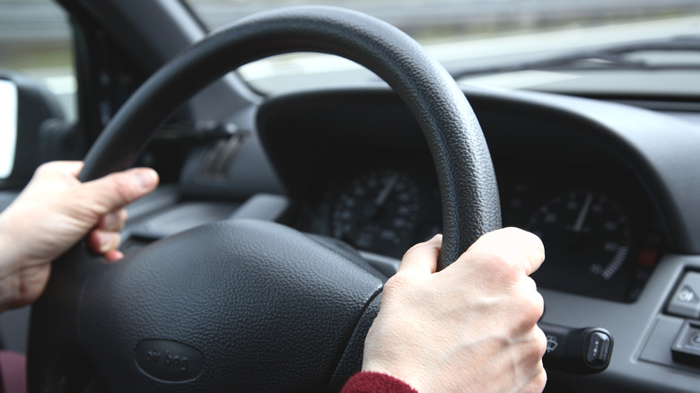 both hands on car steering wheel