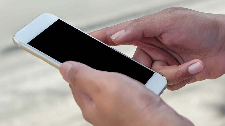 hands holding a smartphone displaying a black screen