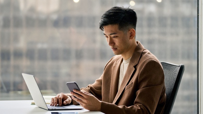 Man using a phone and a laptop