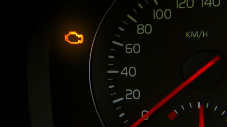 A car dashboard with a lit check engine light symbol