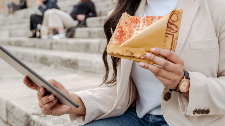 person holding pizza and tablet