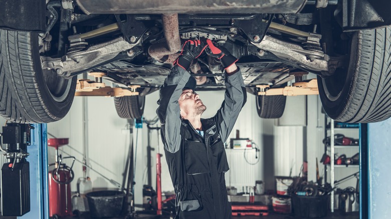 Mechanic under vehicle looking for problems with a drivetrain