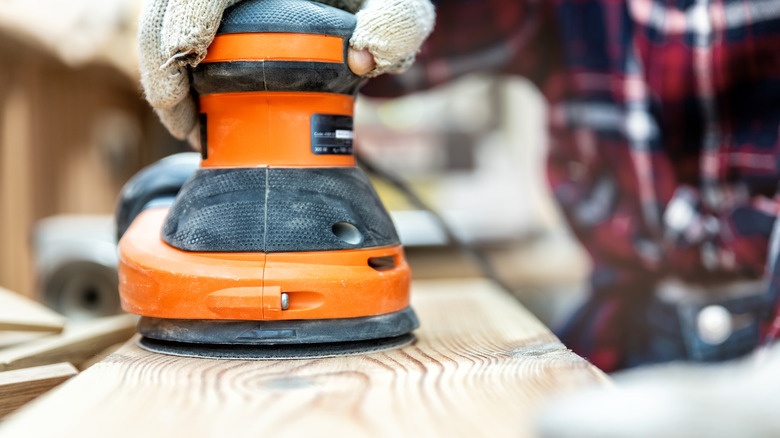 Using orbital sander on plank