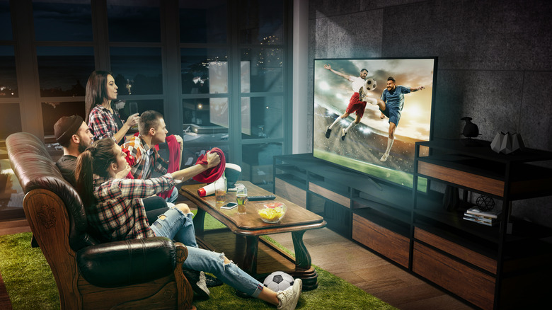 group of people watch soccer match on TV