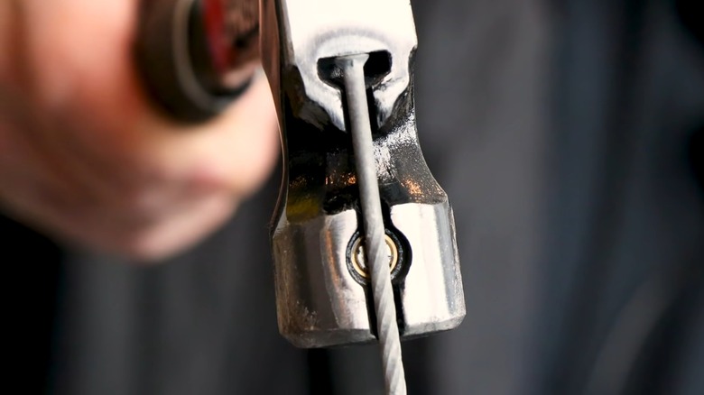 A hammer with a magnetic nail starter holding a nail.