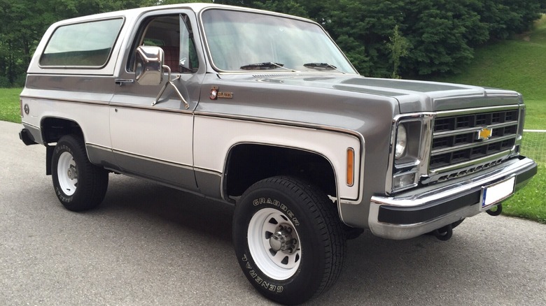 1979 Chevrolet K5 Blazer Cheyenne parked on the roadside, next to a lush green land