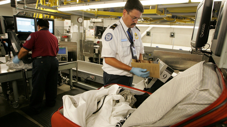 A TSA agent inspects a checked bag