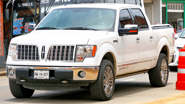 A white Lincoln Mark LT driving on the street, front-left view.