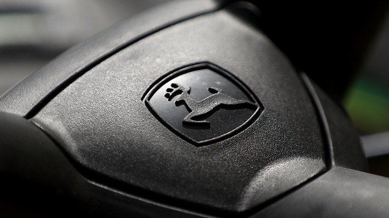 The John Deere badge across the center of a John Deere mower's steering wheel.