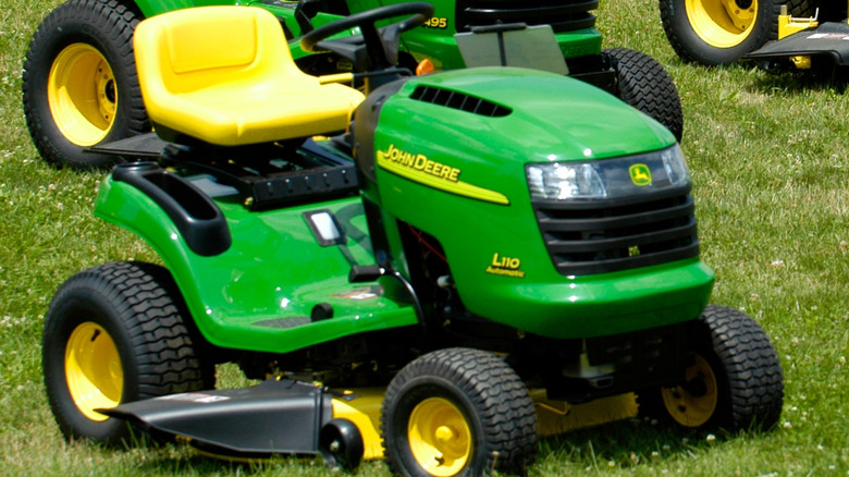 A John Deere riding lawn mower parked on grass.