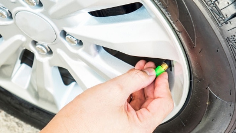 A person installing a green valve stem cap