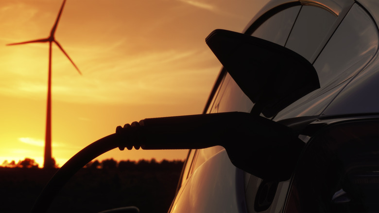 EV charging in front of wind turbine at sunset