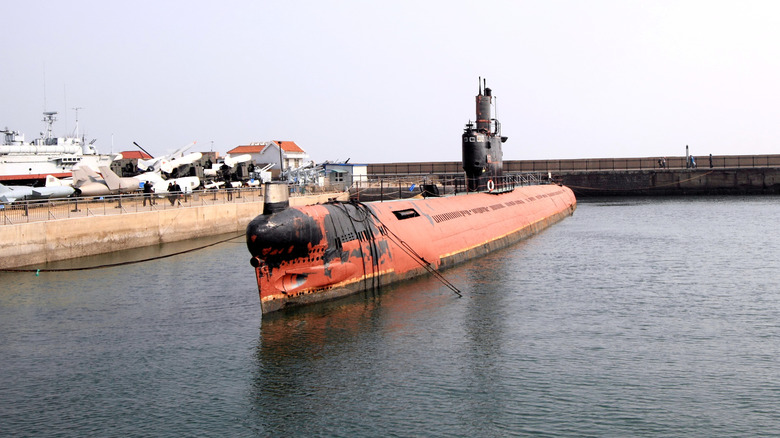 a submarine with grotty-looking re paintwork tied in dock.