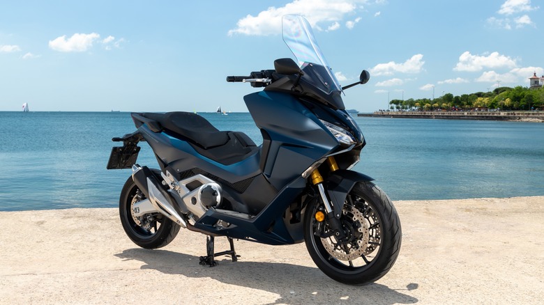 Blue Honda Forza 750 parked by the sea