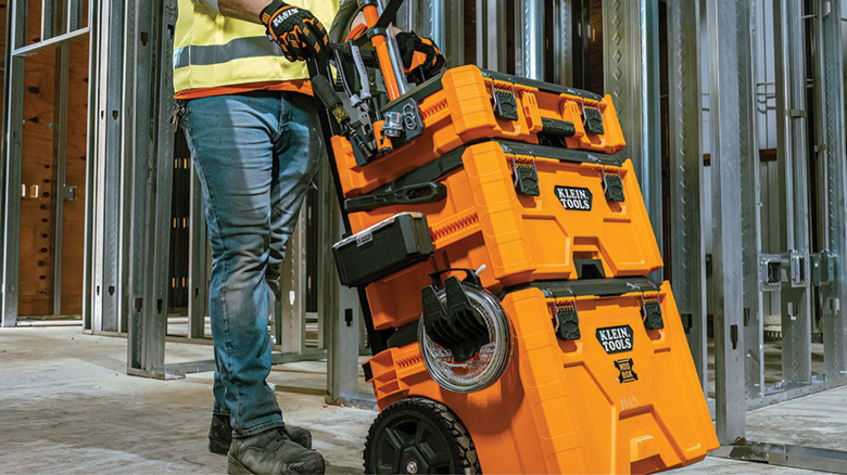 Person rolling a Klein Tools toolboxes across a job site