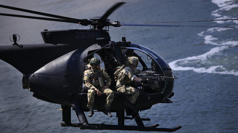 An MH-6 Little Bird with soldiers over the ocean