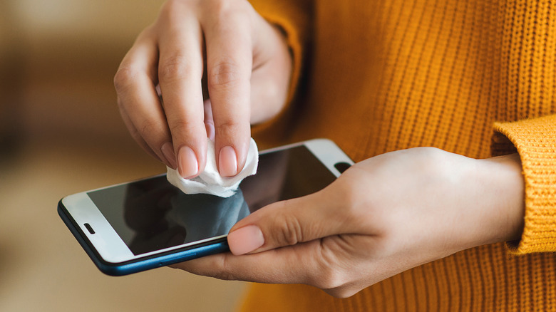 person wiping down a smartphone