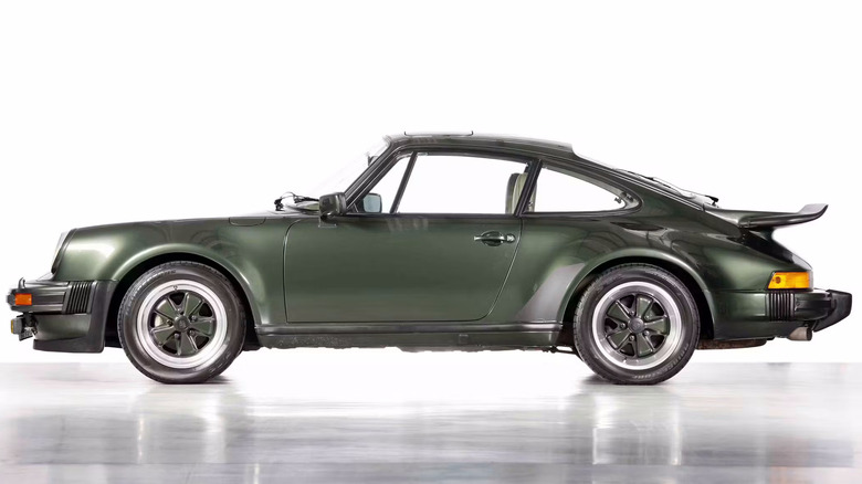 A side view of a metallic green Porsche 911 Turbo sports car.