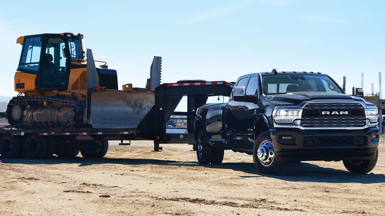 A 2024 Ram 3500HD towing a trailer carrying a large bulldozer.