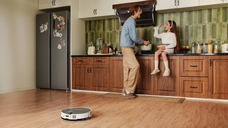 Saros 10 cleaning kitchen floor while a family cooks together.