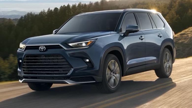 Storm Cloud Toyota Grand Highlander Platinum Hybrid MAX driving with trees in the background