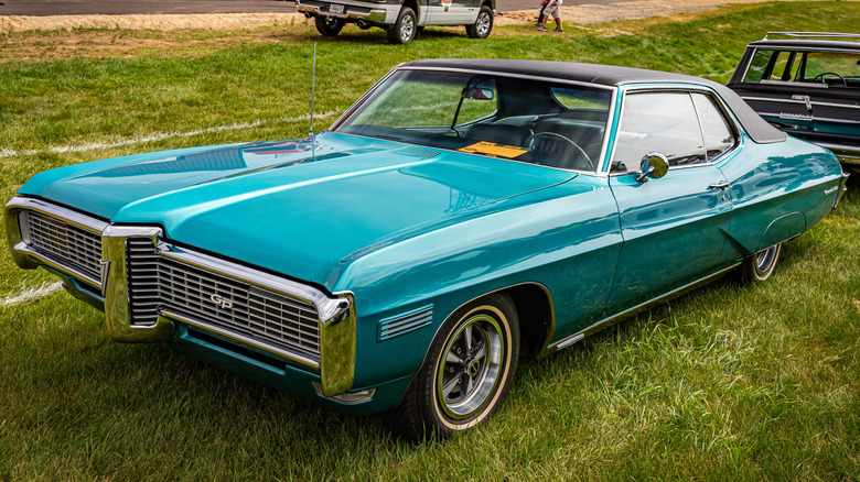 A green 1968 Pontiac Grand Prix vehicle in a park