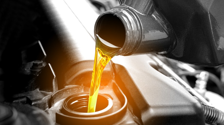 bottle of oil pouring into diesel vehicle 