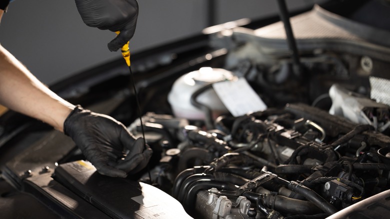 A mechanic checking a car's engine oil level.