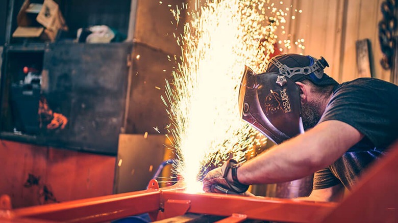 Man in Bad Boy welder mask welding mower components