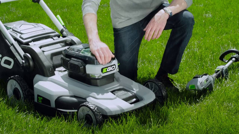 Ego push lawnmower with a man crouching down